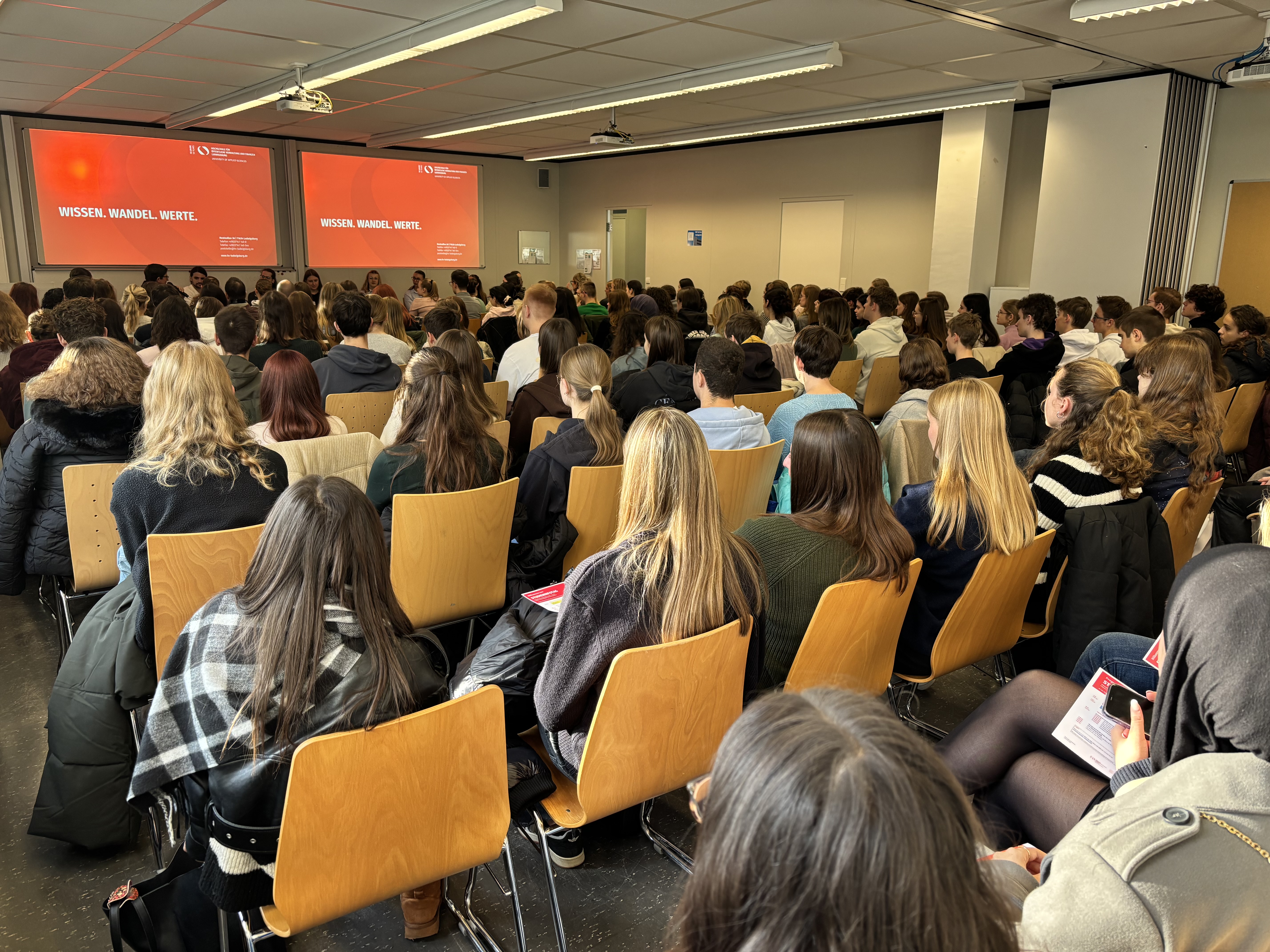 Gefüllter Hörsaal am Studieninfotag der HVF Ludwigsburg, Studieniteressierte hören den Vorträgen zu.
