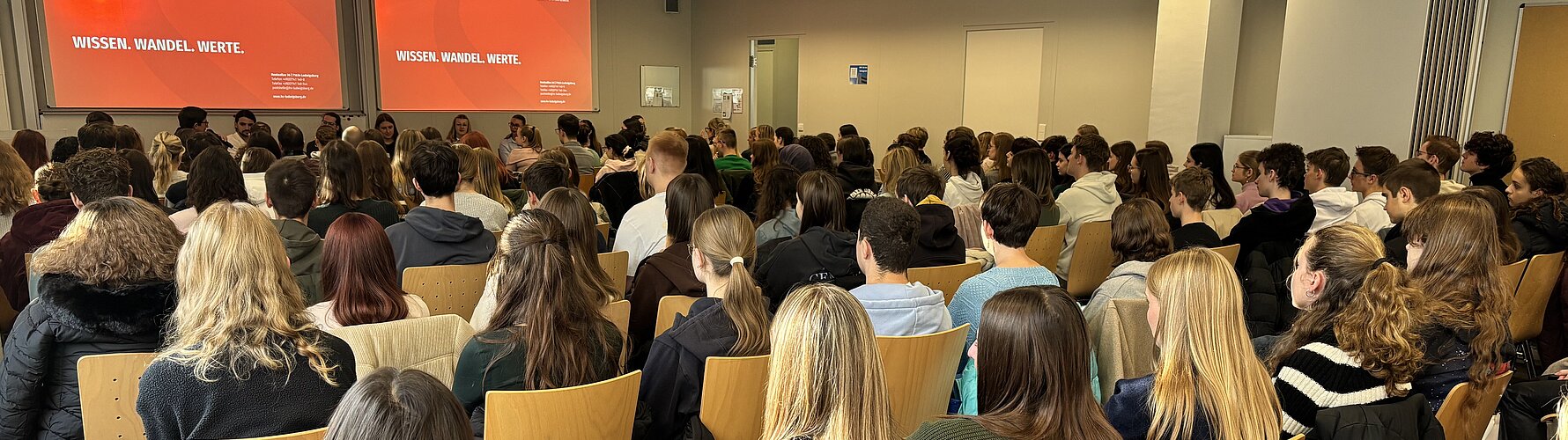 Gefüllter Hörsaal am Studieninfotag der HVF Ludwigsburg, Studieniteressierte hören den Vorträgen zu.