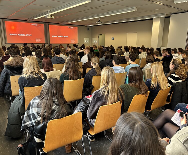 Gefüllter Hörsaal am Studieninfotag der HVF Ludwigsburg, Studieniteressierte hören den Vorträgen zu.