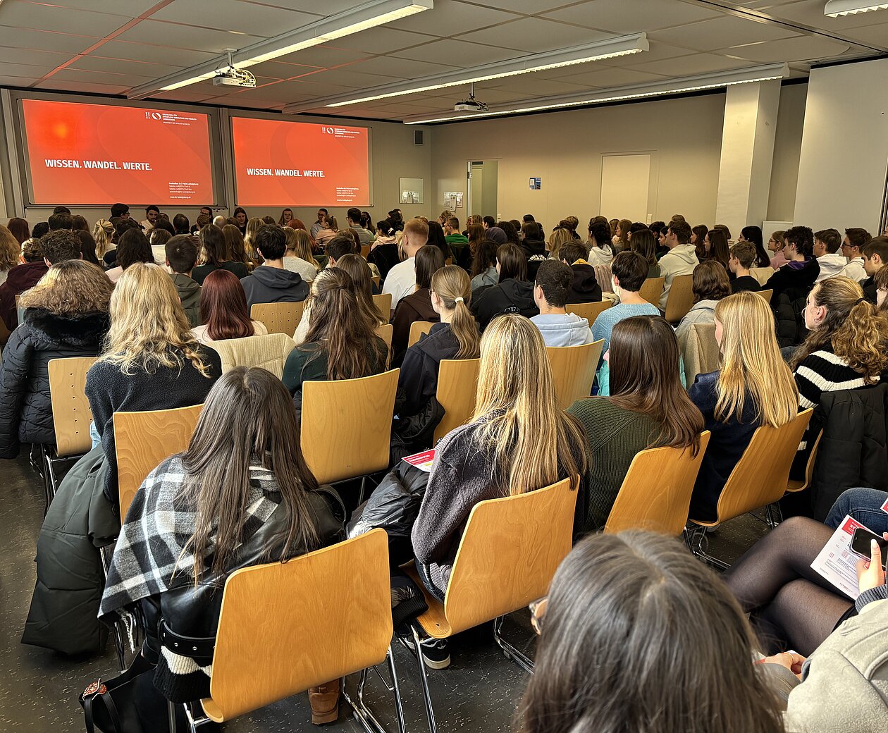 Gefüllter Hörsaal am Studieninfotag der HVF Ludwigsburg, Studieniteressierte hören den Vorträgen zu.