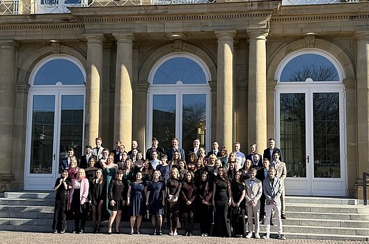 Gruppenfoto der Absolventen des Bachelorstudiengangs Steuerverwaltung Jahrgang 2023 vor dem Neuen Schloss in Stuttgart bei strahlendem Sonnenschein.