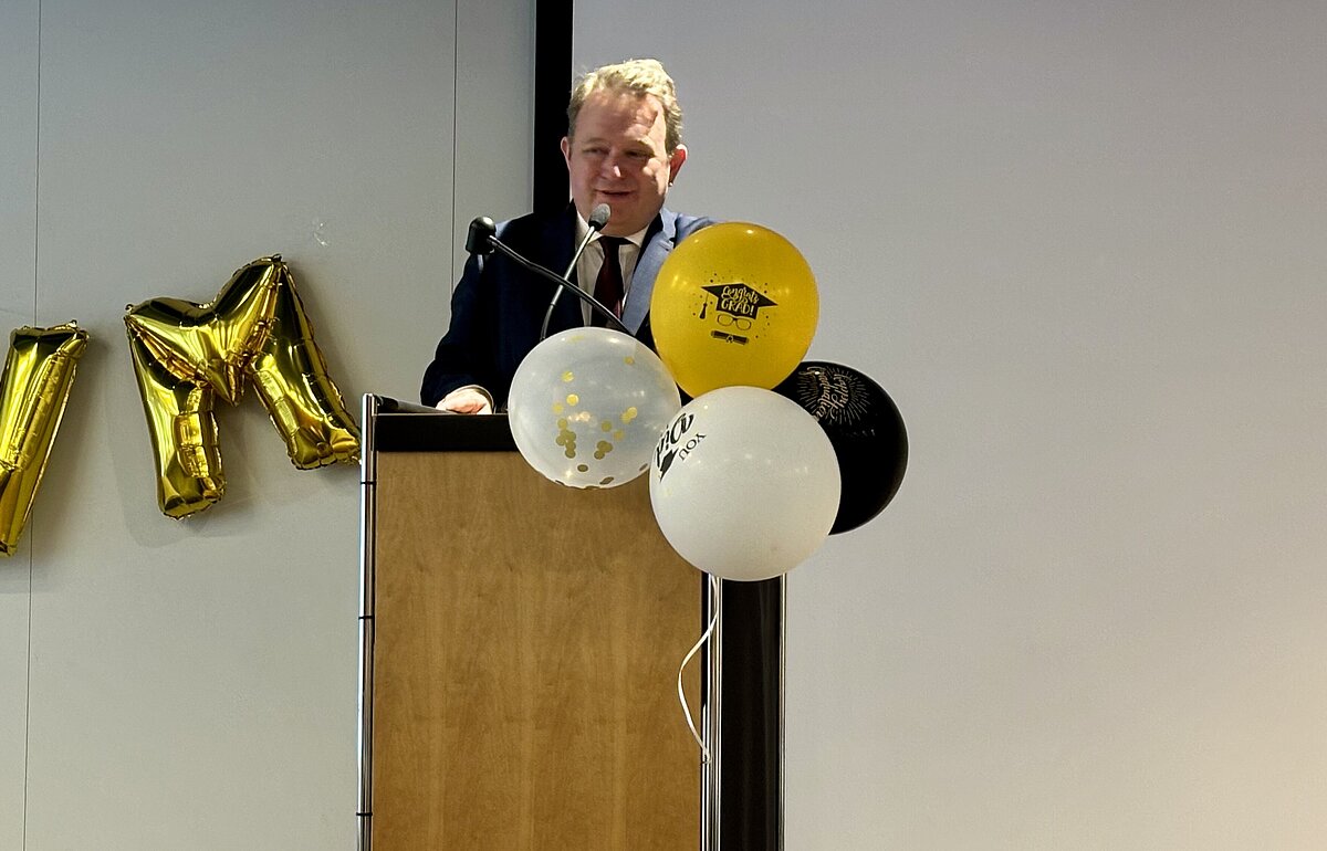 Dekan Prof. Dr. Arne Pautsch hält seine Eröffnungsrede am Rednerpult, vor "DVM"-Ballons und Festdekor.