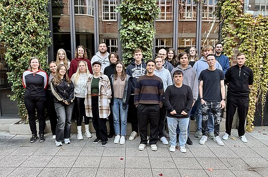 22 DVM-Erstsemester posieren im Freien vor einem mit Efeu bewachsenen Gebäude.