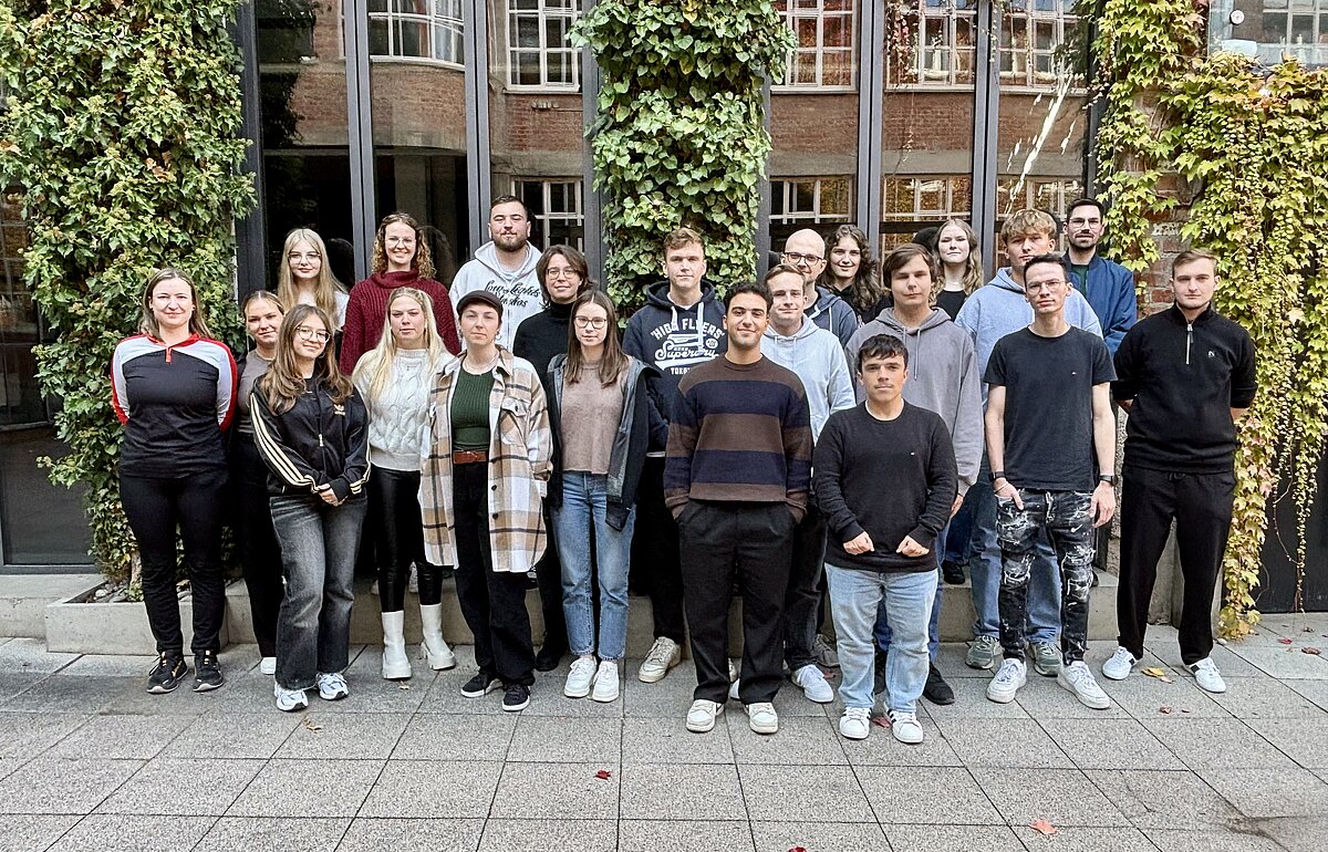 22 DVM-Erstsemester posieren im Freien vor einem mit Efeu bewachsenen Gebäude.