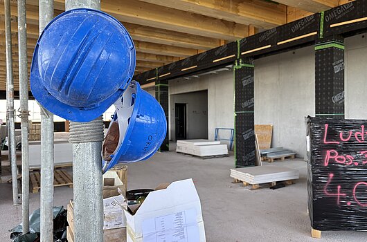 Bauhelme und Baustelle beim Richtfest des Verfügungsgebäudes