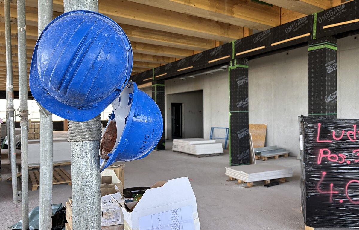 Bauhelme und Baustelle beim Richtfest des Verfügungsgebäudes