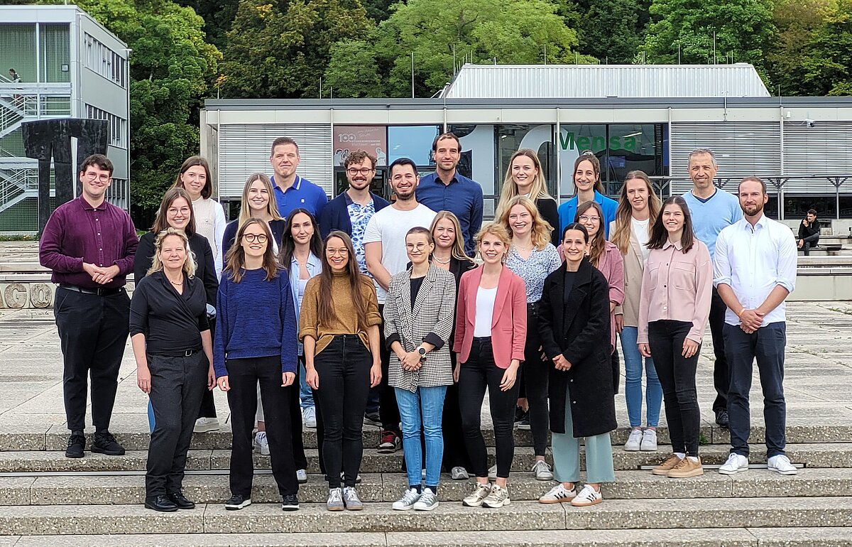 Neue Master-Studierende des Studiengangs Public Management stehen für ein Foto auf einer Treppe am Campus