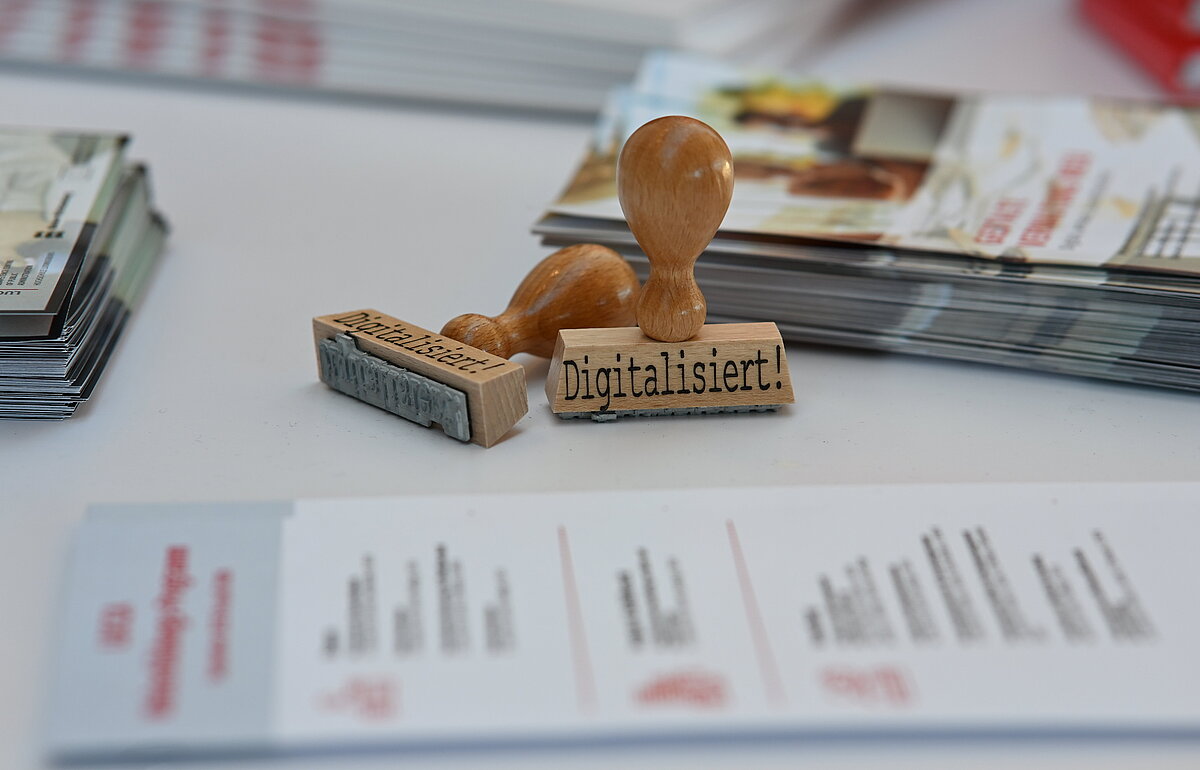 Holzstempel mit der Aufschrift "Digitalisiert!" als Symbol für die digitale Transformation auf der OZG-Taskforce Konferenz.