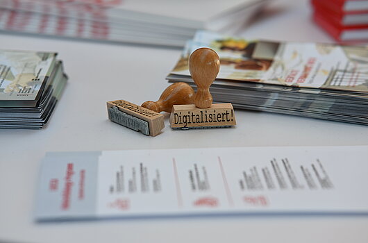Holzstempel mit der Aufschrift "Digitalisiert!" als Symbol für die digitale Transformation auf der OZG-Taskforce Konferenz.