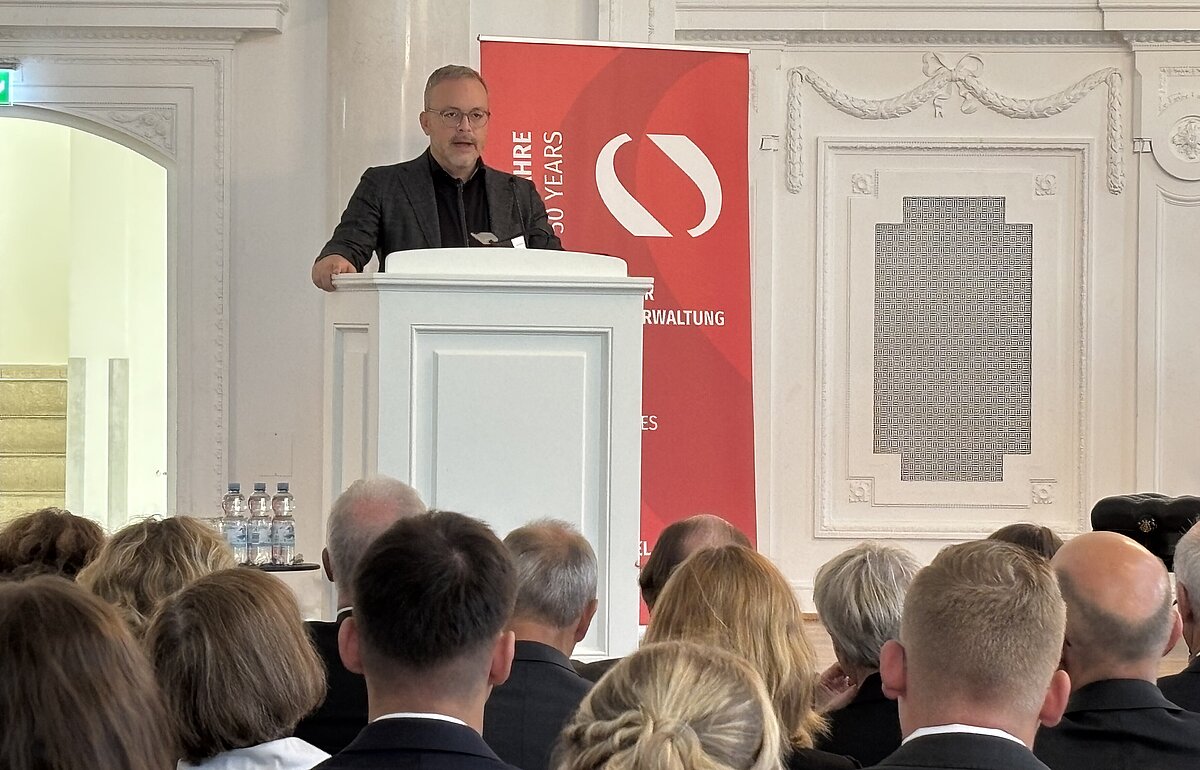 Ministerialdirektor Heiko Engling hält ein Grußwort am Rednerpult für das Finanzministerium Baden-Württemberg.