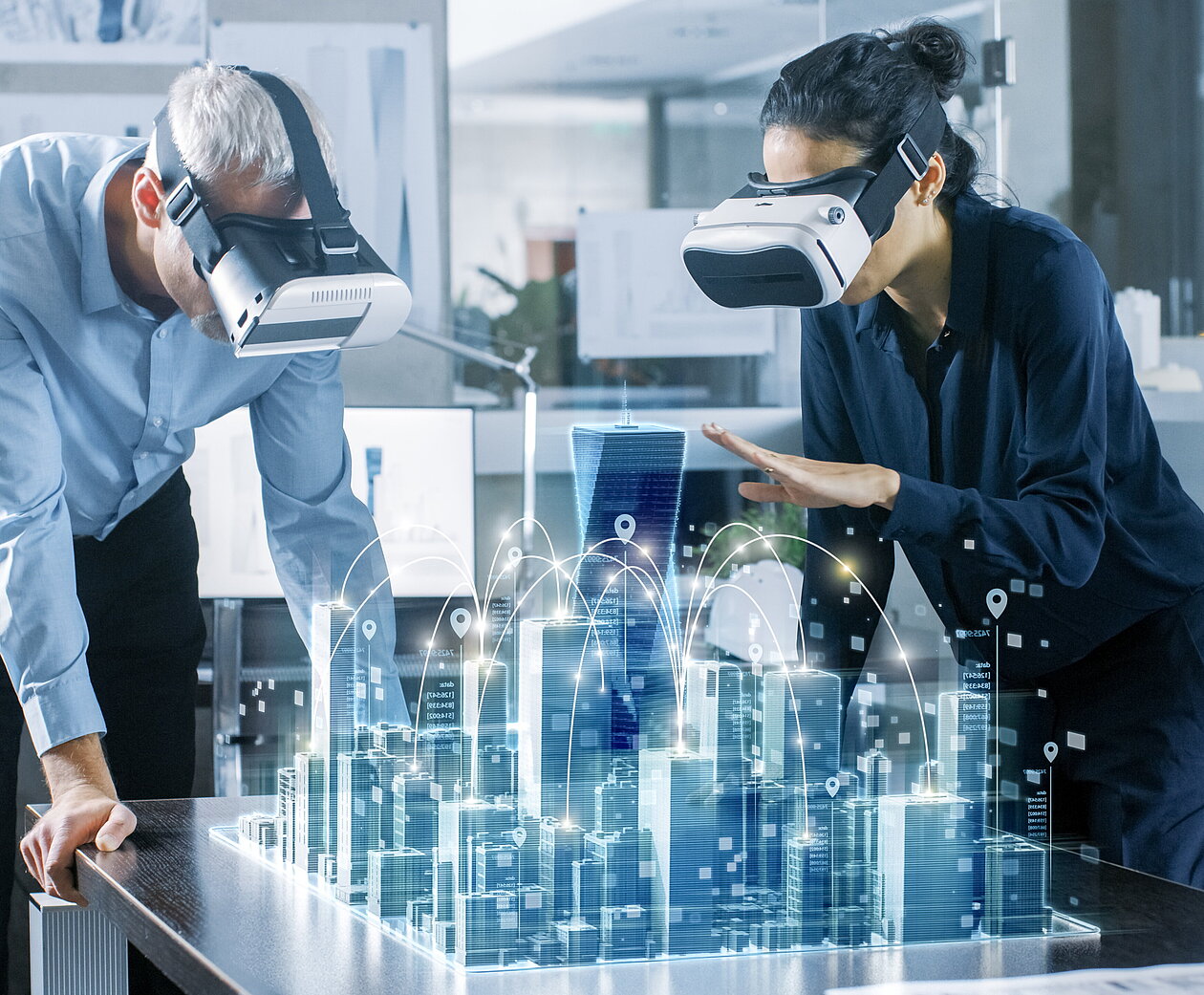 Digitales Verwaltungsmanagement studieren Zwei Personen mit VR-Headsets betrachten ein holografisches 3D-Stadtmodell auf einem Tisch, das eine vernetzte Smart City darstellt.