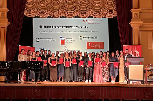 PFM-Absolvent/innen mit Urkunden auf der Bühne