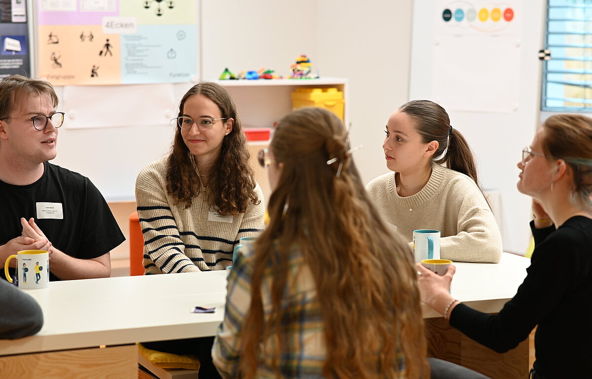 Zwei Studierende stellen ihre Projekte auf der DVM-Fachtagung vor, sitzend an einem Tisch im Austausch.