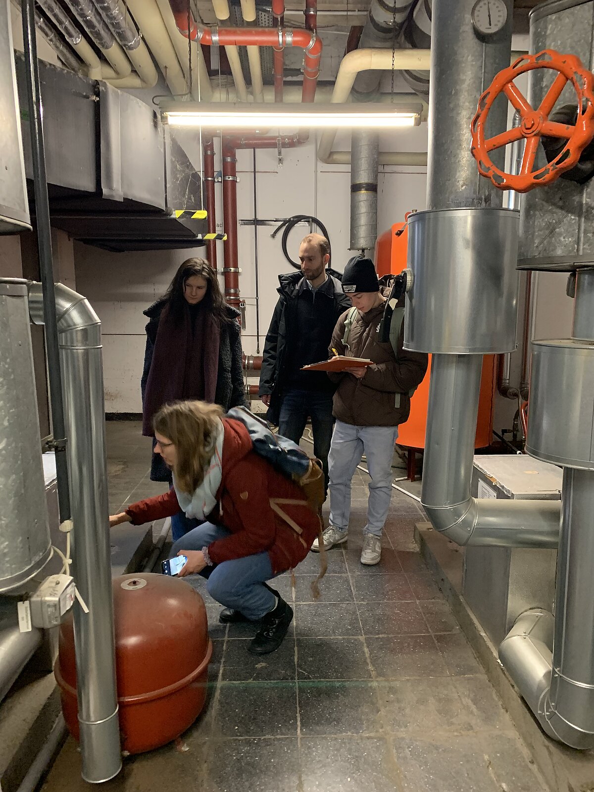 Die Klimaschutzmanager:innen der PH, Frau Lena-Sophie Rehn, und der HVF, Herr Teo Rösslein, begutachten zusammen mit den technischen Expert:innen der Energieagentur Ludwigsburg eine Lüftungsanlage in Gebäude 6.